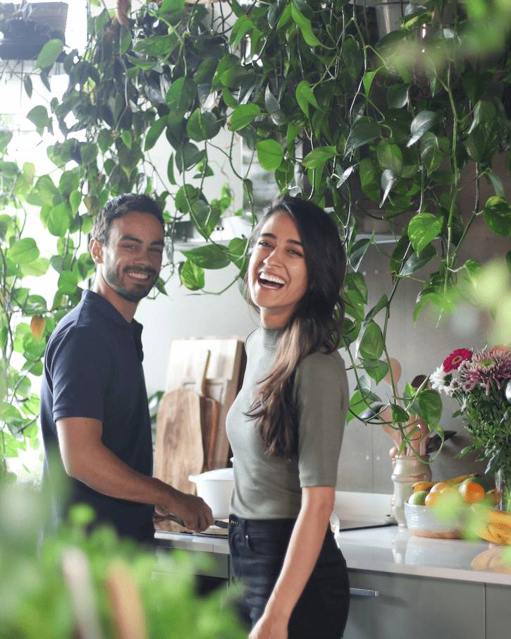 Sadia and Robin in the Pick Up Limes kitchen, smiling and cooking vegan recipes together.